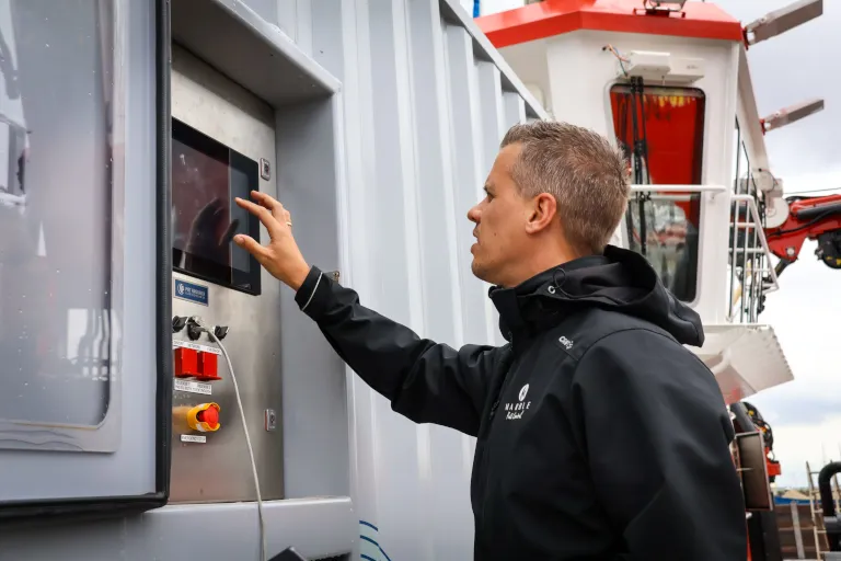 Marble engineer operating a control panel touchscreen next to a workboat wheelhouse
