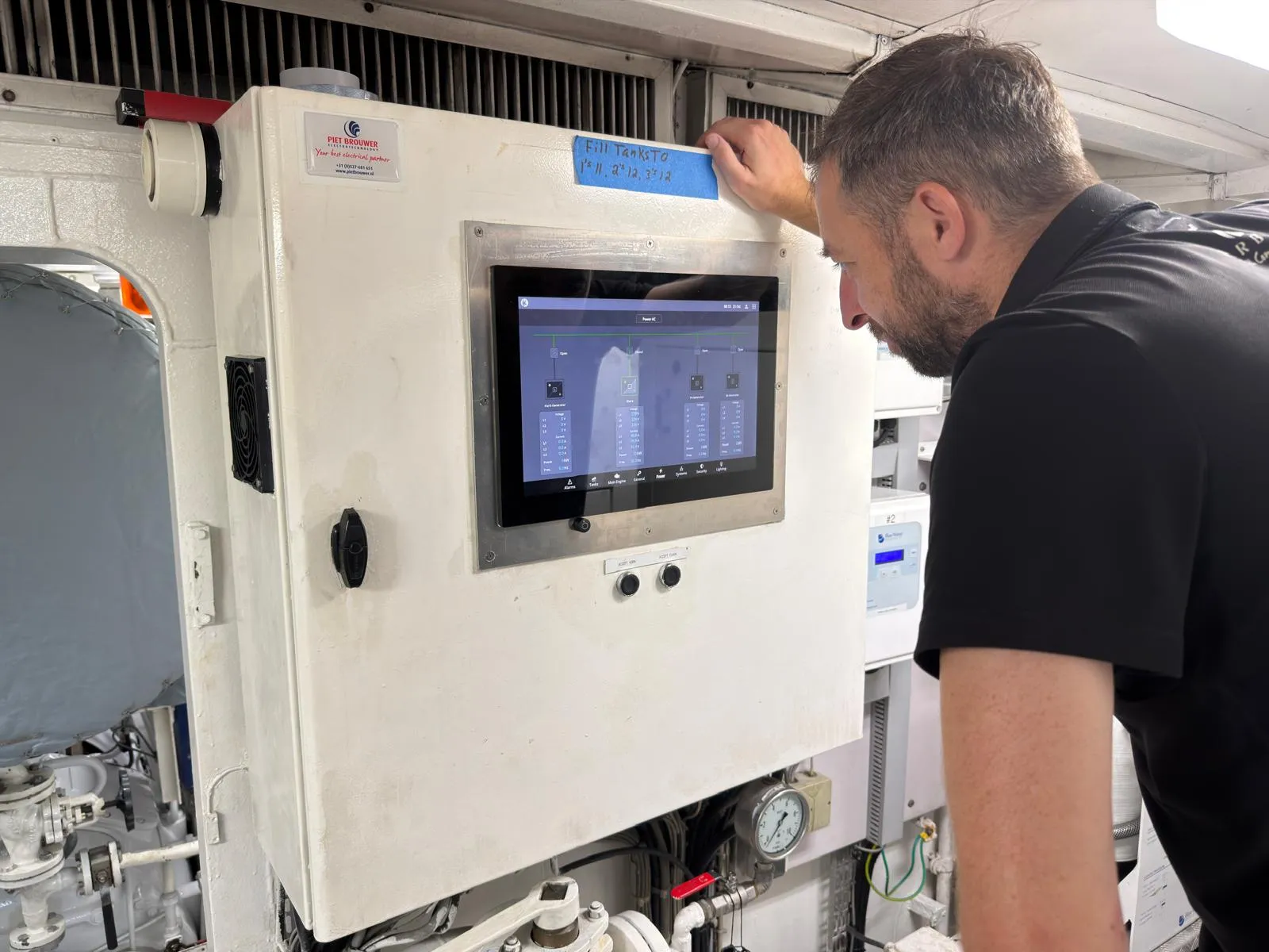 Engineer checking the AC power page on the new HMI panel in Berzinc's engine room