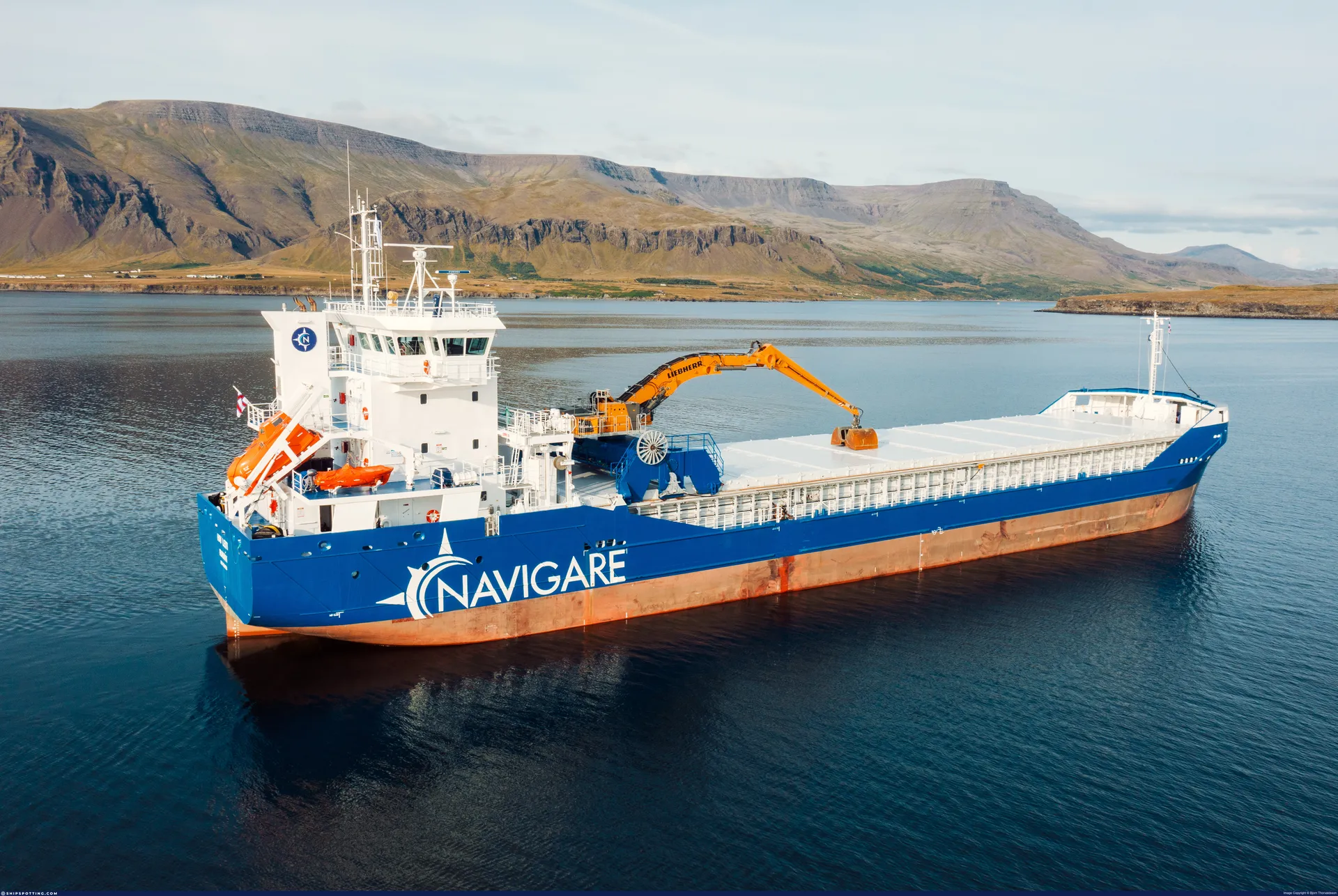 Navigare cargo vessel Hav Fles at anchor in a fjord with its Liebherr excavator over the hatches